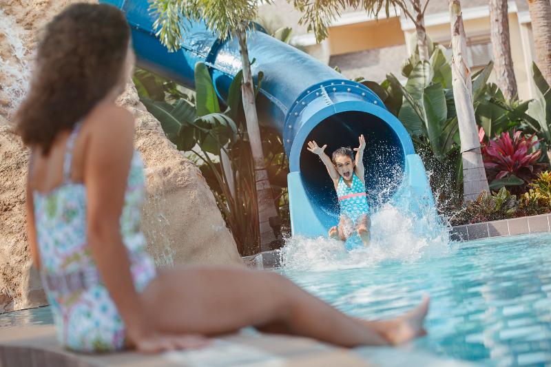 Girl sliding down waterslide while mother watches